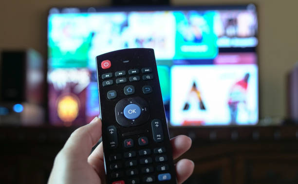 istock Female hand holding a smart tv remote control 1205143482