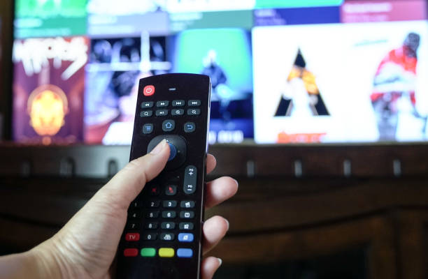 female hand holding a smart tv remote control - remote television movie box imagens e fotografias de stock