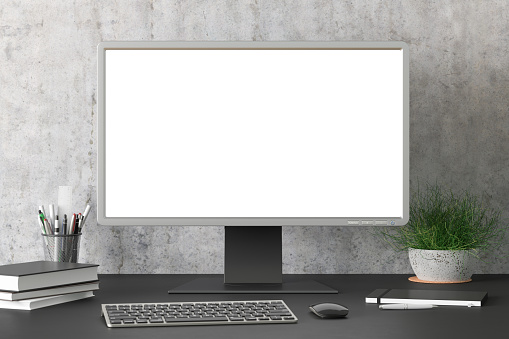 Workspace with blank computer monitor white screen mock up on the black desk near concrete wall.