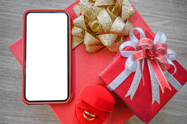 istock White blank screen of phone with gift boxes and ring on wooden background. 1205164080