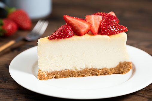 Cheesecake slice with strawberries. Plain New York Classical Style cheesecake on white plate closeup view