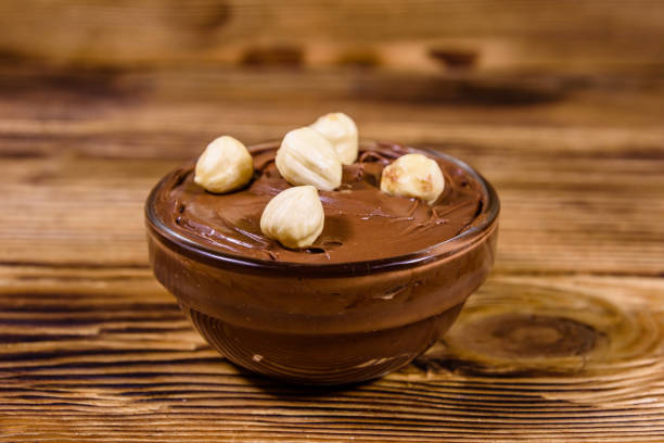 istock Glass bowl with chocolate spread and hazelnuts on a wooden table 1205173624