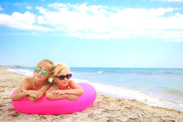 szczęśliwe dziewczyny leżące na różowym nadmuchiwanym kręgu. - inflatable ring zdjęcia i obrazy z banku zdjęć