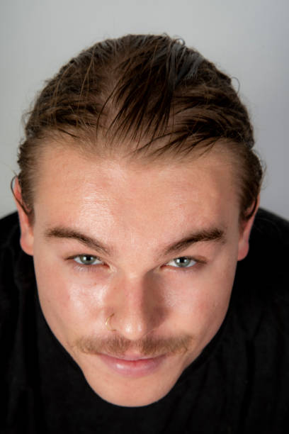 Attractive young man with slicked back hair looks into camera.