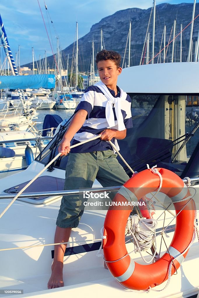 Ragazzo adolescente marinaio ormeggio barca corda in porto - Foto stock royalty-free di 12-13 anni