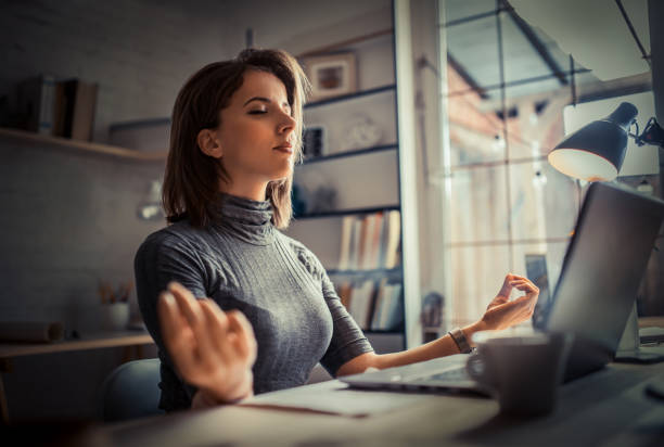 woman in office meditating - yoga business women indoors imagens e fotografias de stock