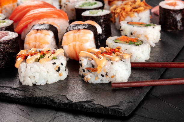 duży zestaw sushi, zbliżenie z pałeczkami na czarnym tle. asortyment różnych maki, nigiri i rolek - sushi california roll salmon sashimi zdjęcia i obrazy z banku zdjęć