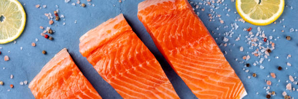 istock Raw salmon with lemon panorama, top shot with salt and pepper 1205195207