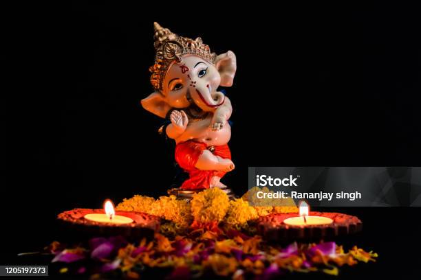 Beautiful Photography Of Ganpati Statue With Two Glowing Lamp And Flowers On The Black Background Faith Concept Stock Photo - Download Image Now