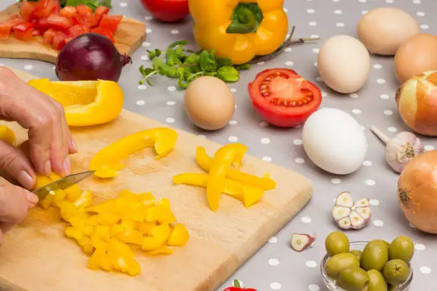 Photo of Hands chop yellow pepper on cutting board