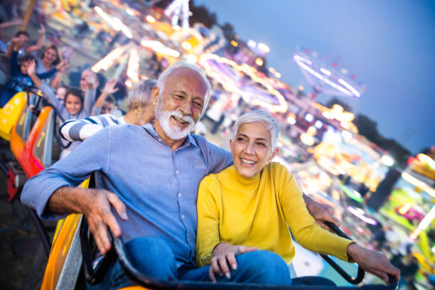 istock Happy senior couple having fun while riding on rollercoaster at amusement park. 1205204950