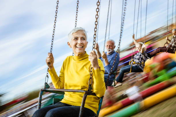 istock Carefree seniors having fun on chain swing ride at amusement park. 1205204968