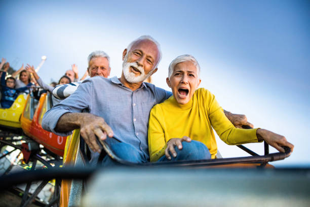 遊園地でジェットコースターに乗りながら楽しんで幸せなシニアカップル。 - rollercoaster carnival amusement park ride screaming ストックフォトと画像