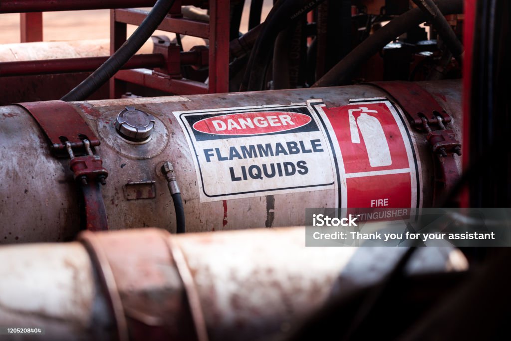 Flammable liquid storage tank. Flammable liquid (such as oil, fuel or hydraulic) container with standard caution sign on the body part. It's using in heavy industry and oil field operation. Flammable Stock Photo