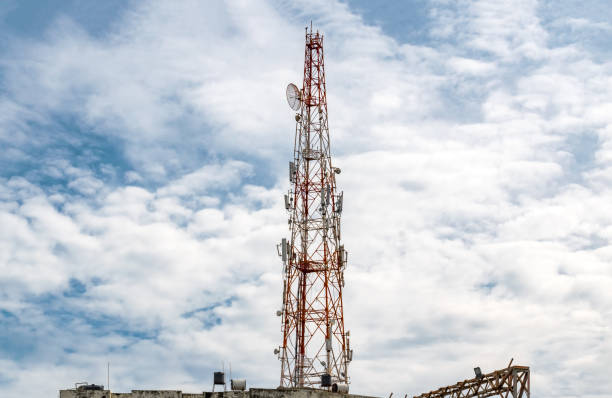 Tall Mobile Phone Tower, Celluar Tower with umbrella dish, attenuators, amplifiers and repeaters, installed on rooftop and is rising high in the Sky with Dramatic Sky background on a sunny noon.