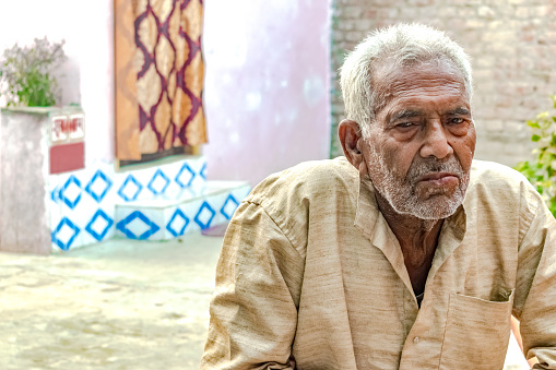 Superannuated old Aged Indian male inide his 80s, usando la ética Khadi Kurta, está en profunda tristeza y dando una expresión sombría de soledad y depresión. Tiene arrugas en la cara y pelo blanco recortado. photo