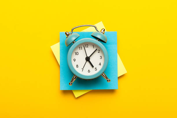 istock Blue analog clock on a stack of note paper. Business time distribution, reminders and checklist 1205211795