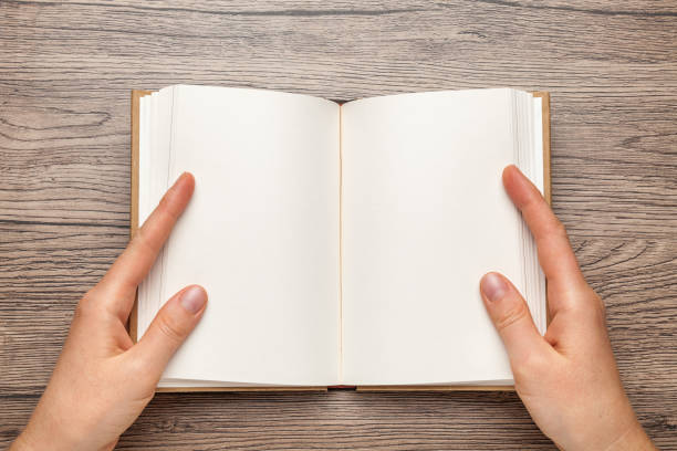 istock A5 open book mockup with hands. Empty template of page. Blank for design. On wooden background 1205211932