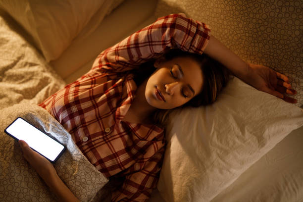 istock Young woman in bed has fallen asleep with phone in her hand 1205212455