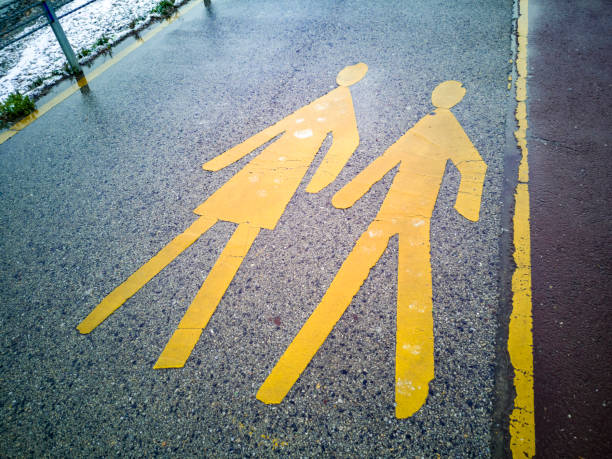 In a rainy day, yellow pedestrian sign on wet asphalt.