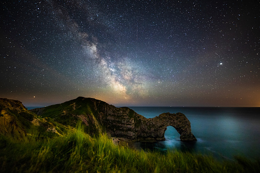 Night sky with milky way moving over the famous Durdle Door on the Jurassic Coastline of Dorset, UK