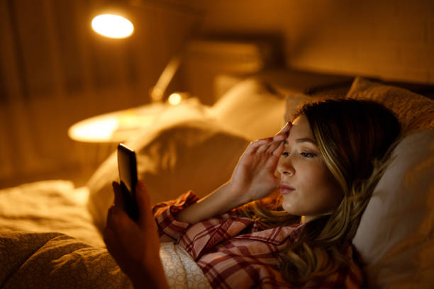 istock Beautiful young woman using mobile phone in bed 1205213557