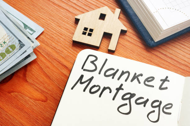 istock Blanket mortgage written phrase and model of home. 1205213963
