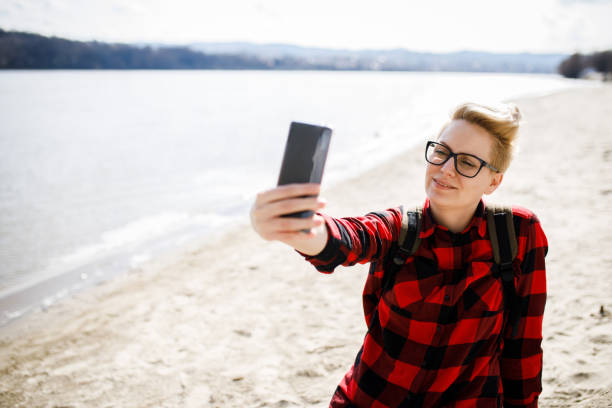 istock young woman on the  beach. She is taking a selfie 1205214978