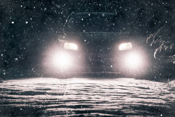 istock Snow falls on the road in the headlights 1205217560