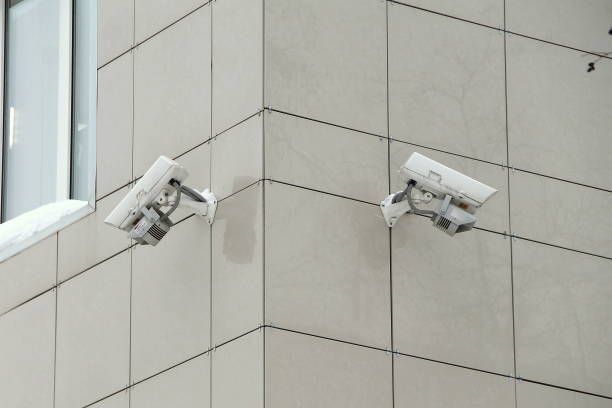 istock Surveillance camera mounted on tiled wall of house 1205220038