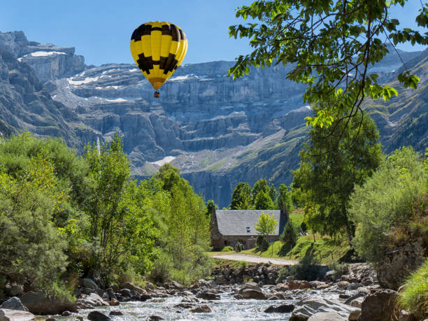 a view of Cirque de Gavarnie with yellow hot air balloon, Hautes-Pyrenees, France a view of Cirque de Gavarnie with yellow hot air balloon, Hautes-Pyrenees, France gavarnie stock pictures, royalty-free photos & images
