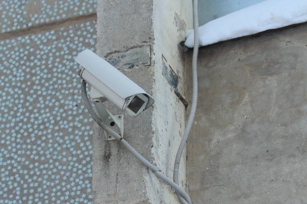 istock Surveillance camera mounted on tiled wall of house 1205223281