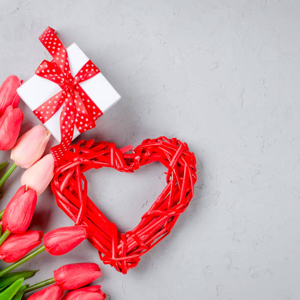 istock nice wicker red heart with gift box and red tulips on old grey background. Valentines day decoration on old background. Copy space. 1205224860