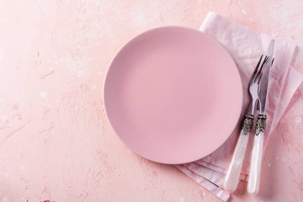 istock Pink plate, cutlery and napkin on stone table top view. Table setting. 1205226262