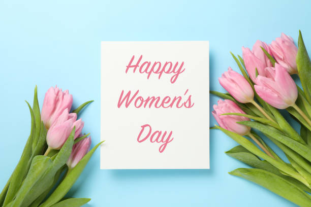 istock Inscription Happy Women's Day on blue background with tulips, top view 1205227657
