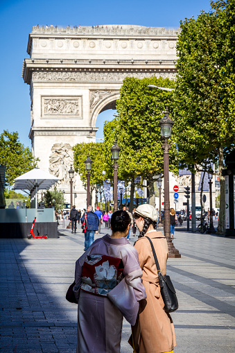 Paris/France - September 10, 2019 : Two Japanese tourist taking pictures in front of the Arc de Triomphe on Champs-Elysees avenue