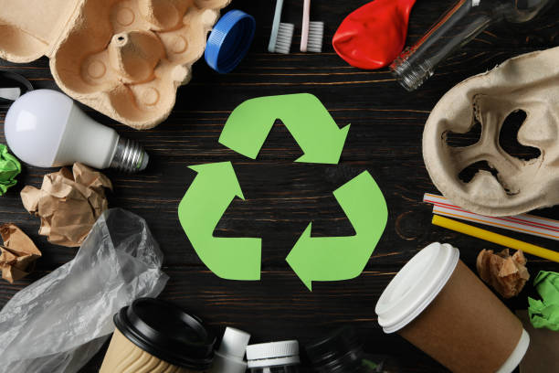 istock Recycle sign on wooden background with different trash, top view 1205228157