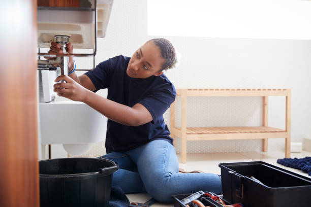 istock Female Plumber Working To Fix Leaking Sink In Home Bathroom 1205228915