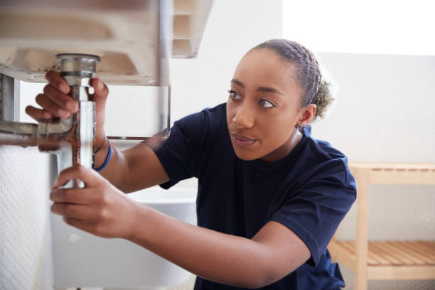 istock Female Plumber Working To Fix Leaking Sink In Home Bathroom 1205229523