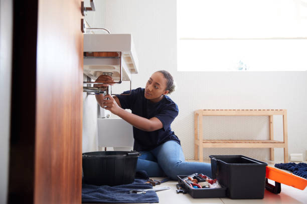 istock Female Plumber Working To Fix Leaking Sink In Home Bathroom 1205229566