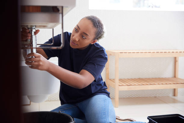istock Female Plumber Working To Fix Leaking Sink In Home Bathroom 1205229618