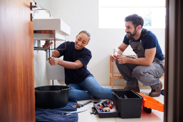 Male Plumber Teaching Female Apprentice To Fix Leaking Sink In Home Bathroom Male Plumber Teaching Female Apprentice To Fix Leaking Sink In Home Bathroom Plumber stock pictures, royalty-free photos & images