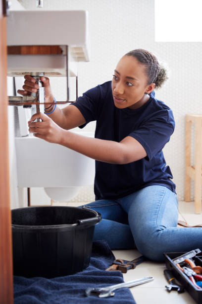 istock Female Plumber Working To Fix Leaking Sink In Home Bathroom 1205230047