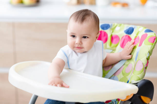 istock Cute baby sitting in high chair in kitchen 1205230976