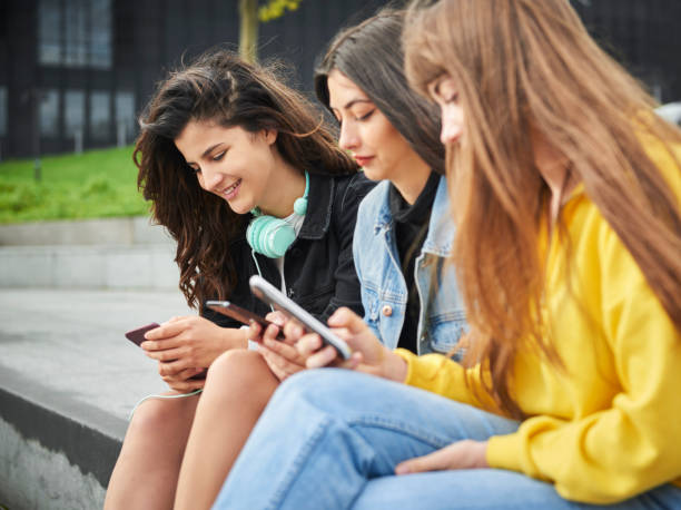istock Side view of three girls using their smart phone 1205232381