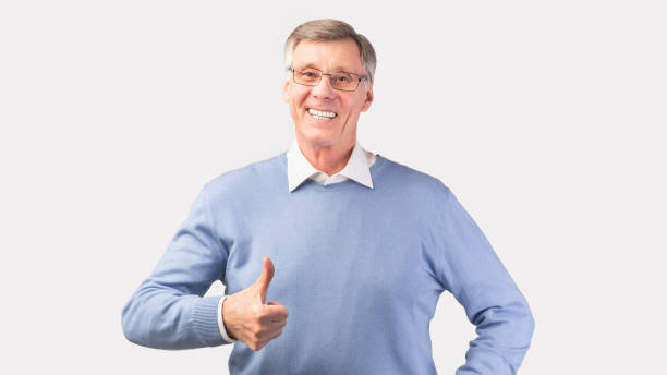 istock Happy Senior Man Gesturing Thumbs Up Standing, White Background, Panorama 1205233454