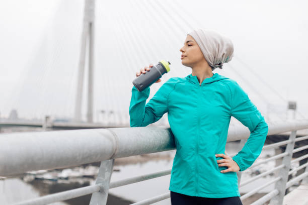 istock Young woman standing and drinking water 1205233548