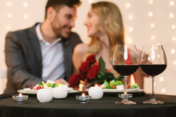 istock Affectionate couple dating in restaurant, glasses with red wine in foreground 1205233853