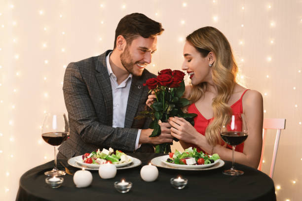 istock Handsome Man Presenting Roses To Happy Girlfriend On Date In Restaurant 1205233909
