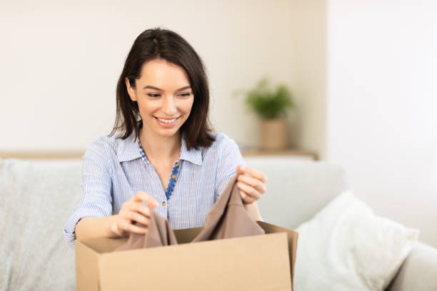 istock Happy girl putting clothes in cardboard box 1205235237